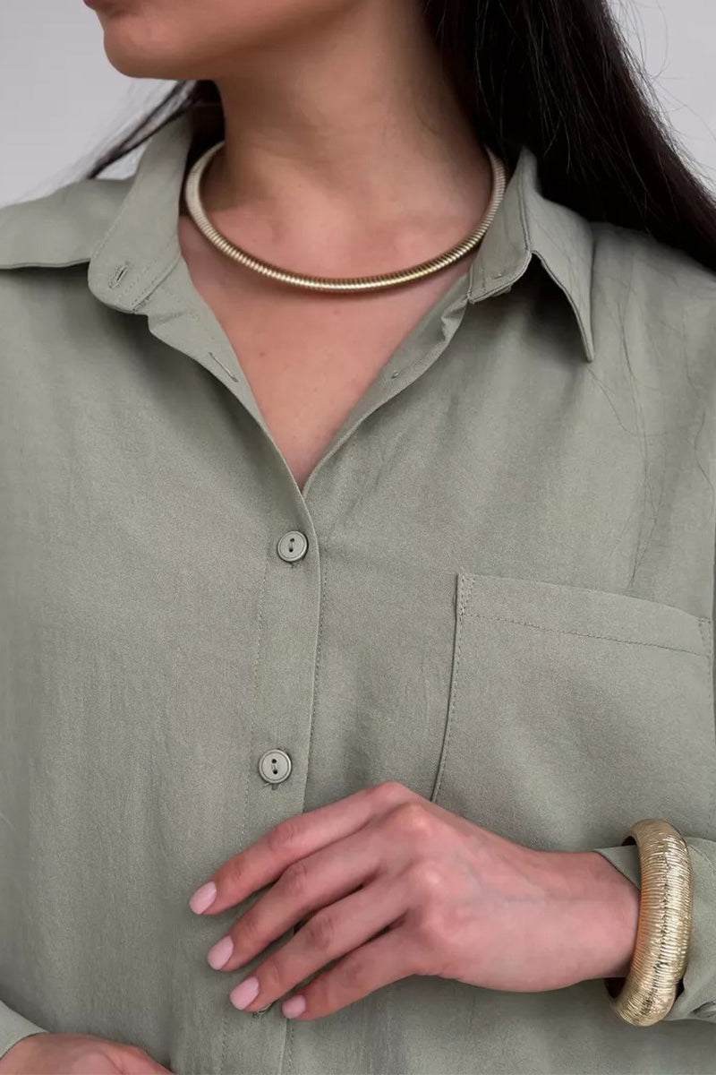 Close-up of woman wearing relaxed fit wide-leg two-piece set in light green with gold necklace and bracelet