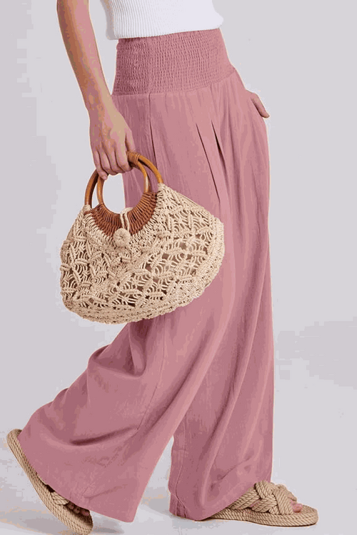 Woman wearing oversized linen leaved-in set with flowy pink palazzo pants and woven handbag