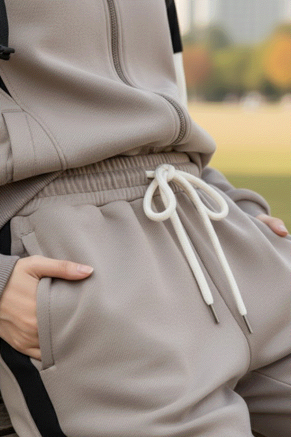 Close-up of beige Comfort in Motion athleisure tracksuit with drawstring waist and hands in pockets