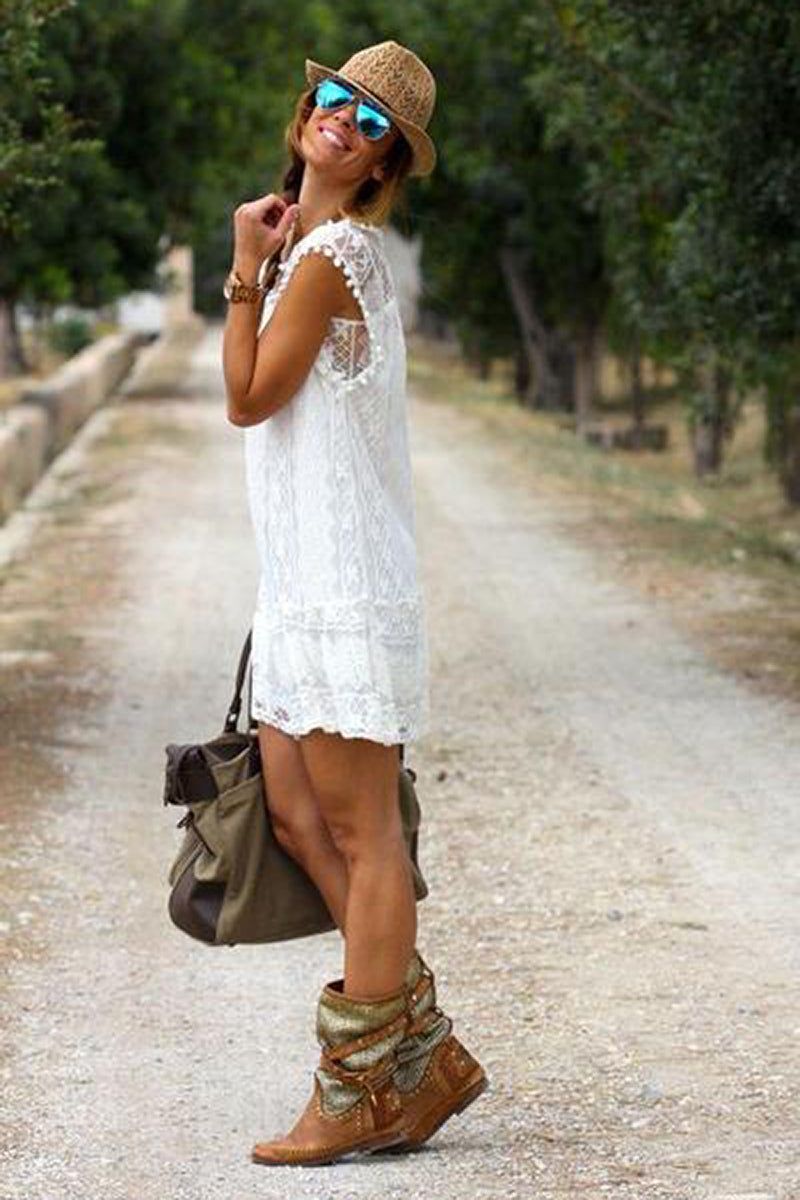 Woman wearing a white pom pom lace mini dress with sleeveless design and carrying a brown bag outdoors