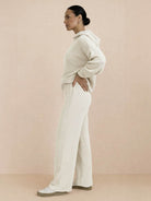 Woman wearing beige waffle-knit two-piece hoodie and pants set, side view, casual comfortable outfit