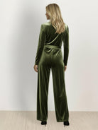 Woman wearing a deep V-neck velvet suit with long sleeves, removable waist tie, and wide-leg pants