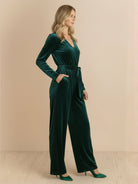 Woman wearing a deep V-neck velvet suit with long sleeves, removable waist tie, and wide-leg pants.