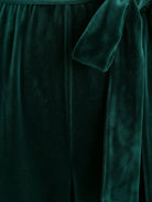 Woman wearing a deep V-neck velvet suit with long sleeves, removable waist tie, and wide-leg pants at an elegant event