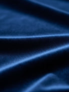 Woman wearing deep V-neck velvet suit with long sleeves, removable waist tie, and wide-leg pants at formal event