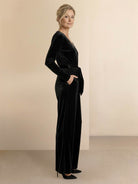 Woman wearing a deep V-neck velvet suit with long sleeves, removable waist tie, and wide-leg pants.