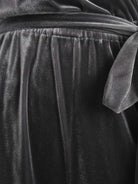 Woman wearing deep V-neck velvet suit with long sleeves and wide-leg pants