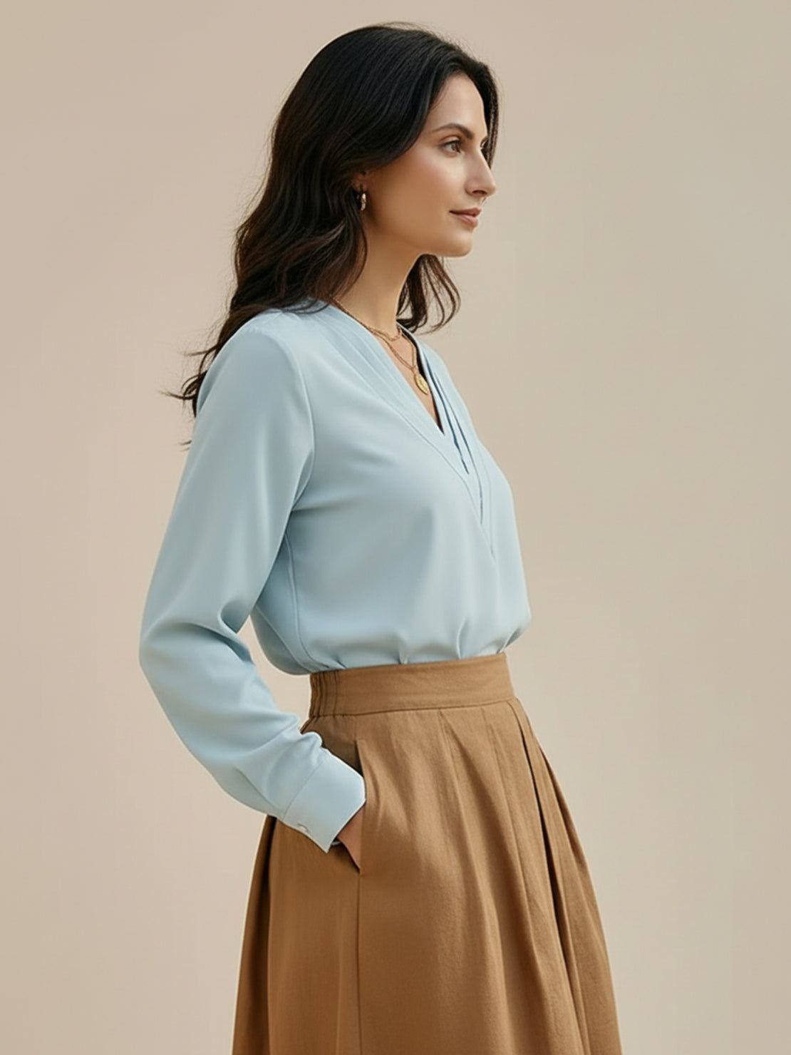 Woman wearing a pleated V-neck long-sleeve blouse with relaxed fit and button cuffs