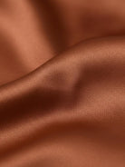 Silk-finish button front shirt with smooth fabric, traditional collar, relaxed fit, and curved hem.