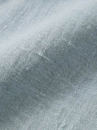 white Tencel-linen pleated wide-leg pants with structured waist closure and floor-skimming silhouette