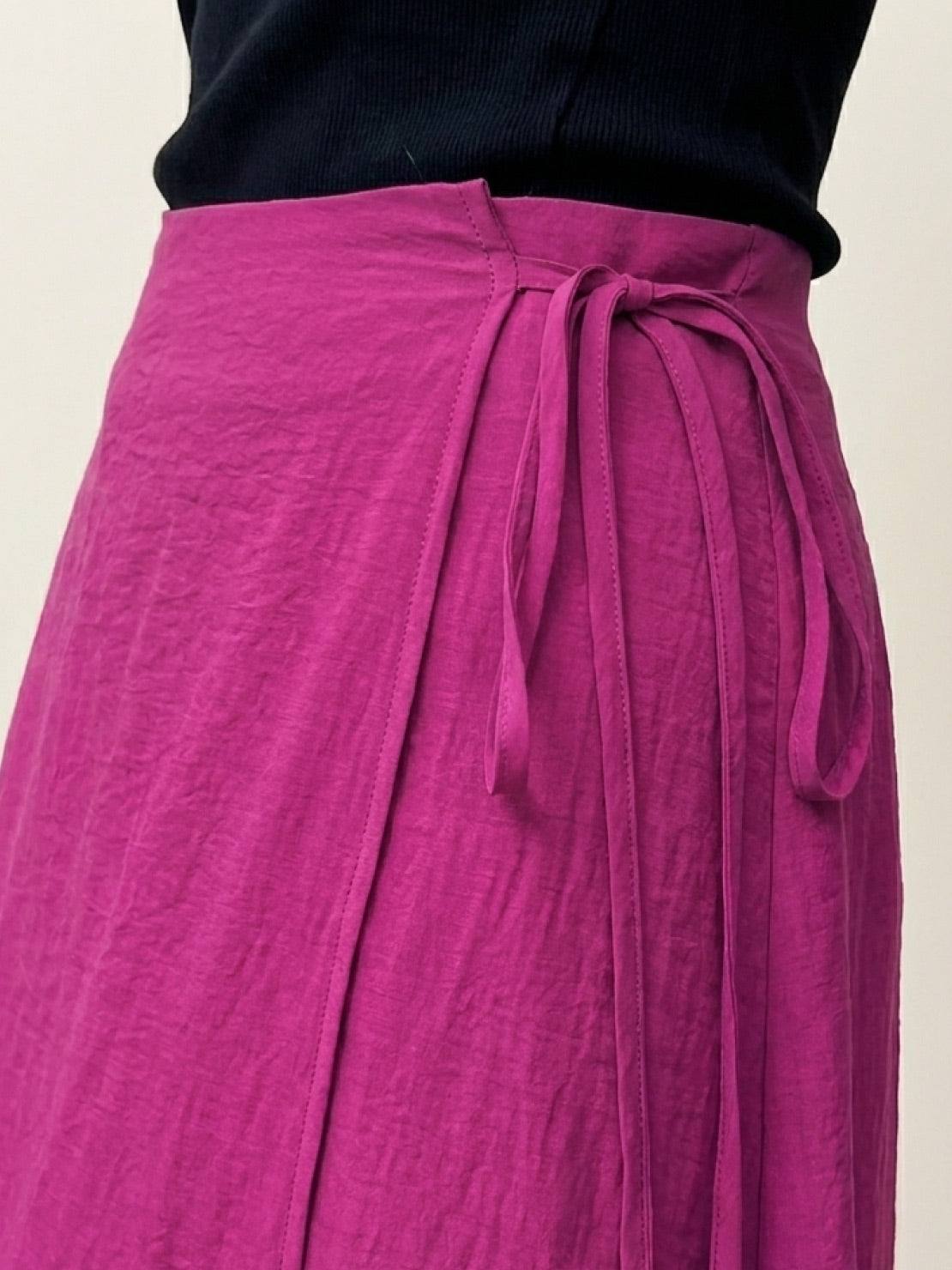 Woman wearing asymmetrical wrap maxi skirt with side tie closure and asymmetric hem in lightweight fabric