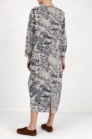 Back view of a midi dress featuring a Japanese porcelain print in blue on light beige fabric, with 3/4 sleeves and a rear slit