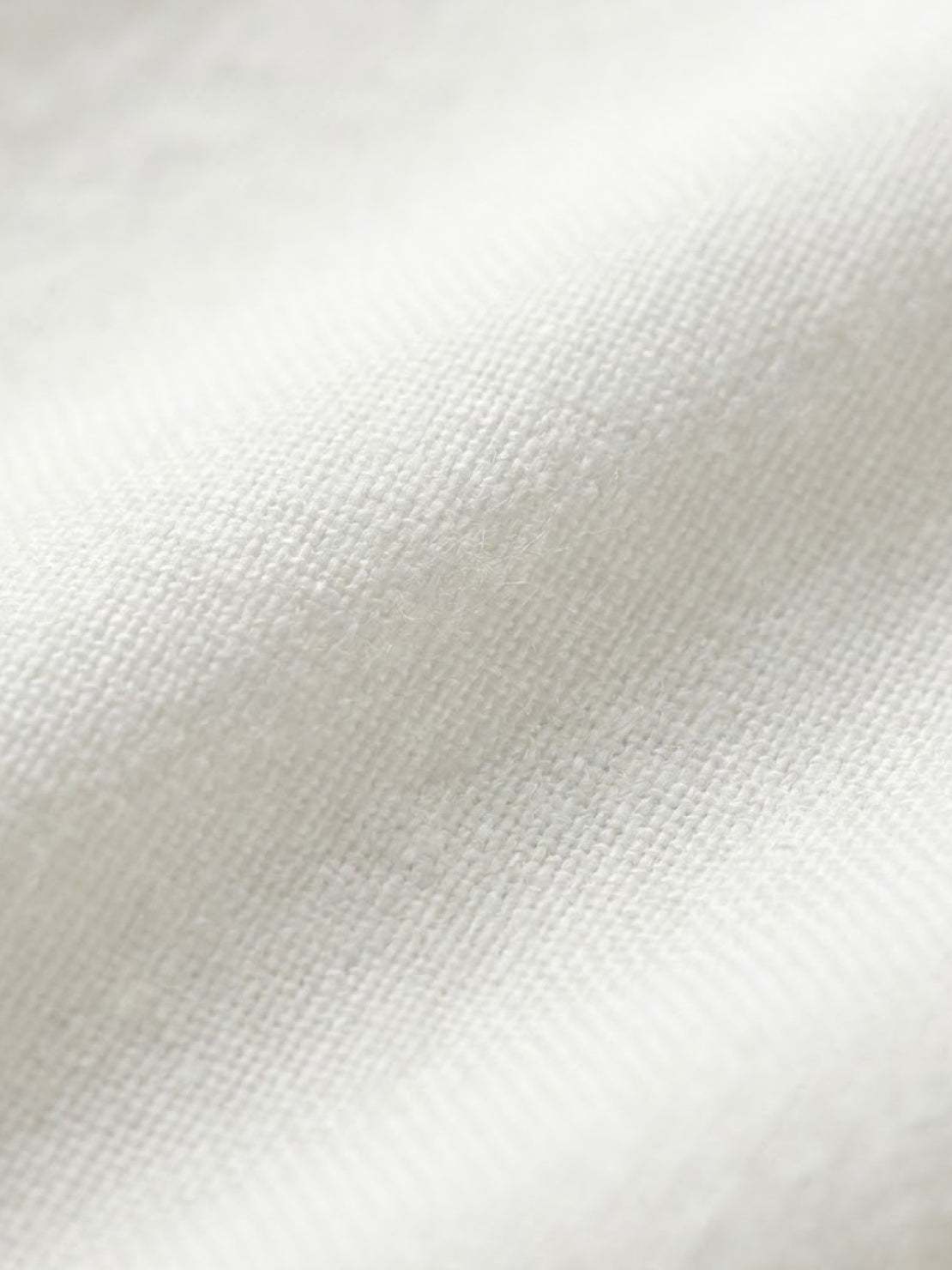 Close-up of soft white cotton fabric texture for short-sleeved pullover and wide trouser matching set
