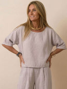 Woman wearing a light gray short-sleeved pullover and wide trouser matching set with relaxed fit and round neckline