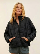 Woman wearing a black lightweight puffer travel jacket with front pockets and zipper closure
