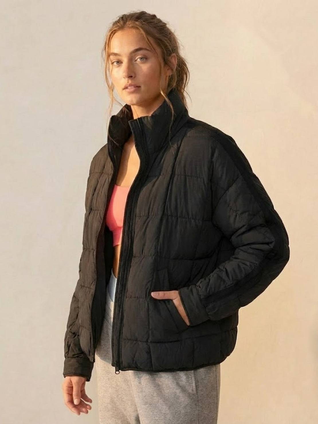 Woman wearing a black lightweight puffer travel jacket with zip front and side pockets