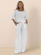 Woman wearing white short-sleeved pullover and wide trouser matching set made of breathable cotton with deep pockets and loose fit.