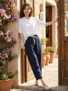 Woman wearing breezy relaxed fit straight pants in black while sitting on wooden floor