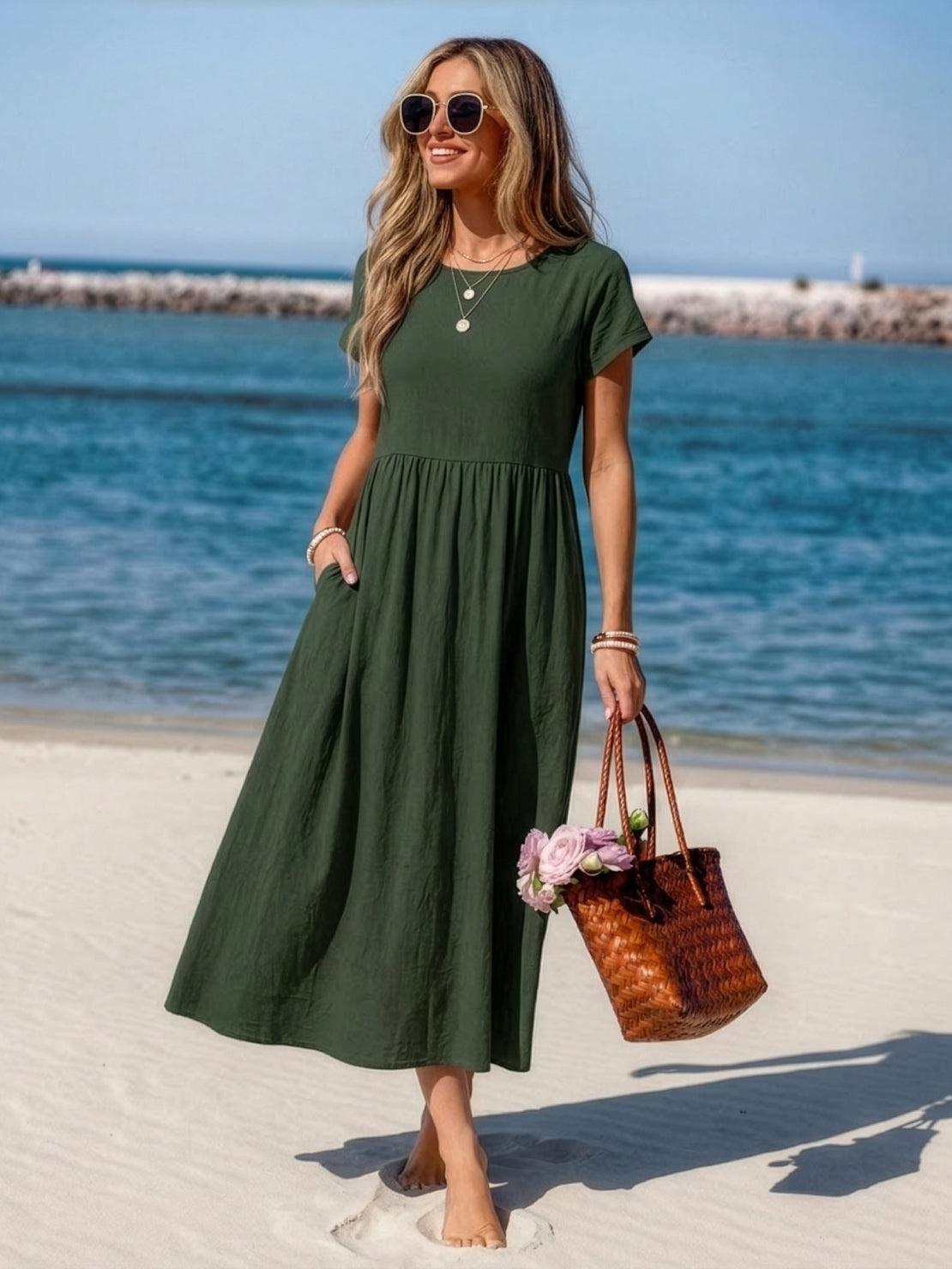 Woman wearing a capped-sleeve voluminous pleated midi dress with flowy fabric and pockets