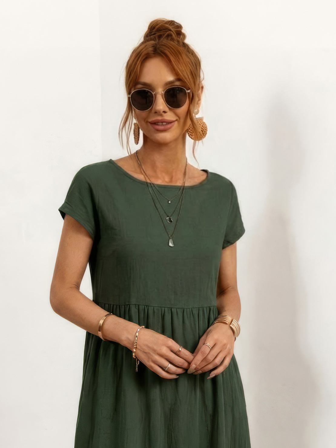 Woman wearing capped-sleeve voluminous pleated midi dress with flowing skirt and pockets