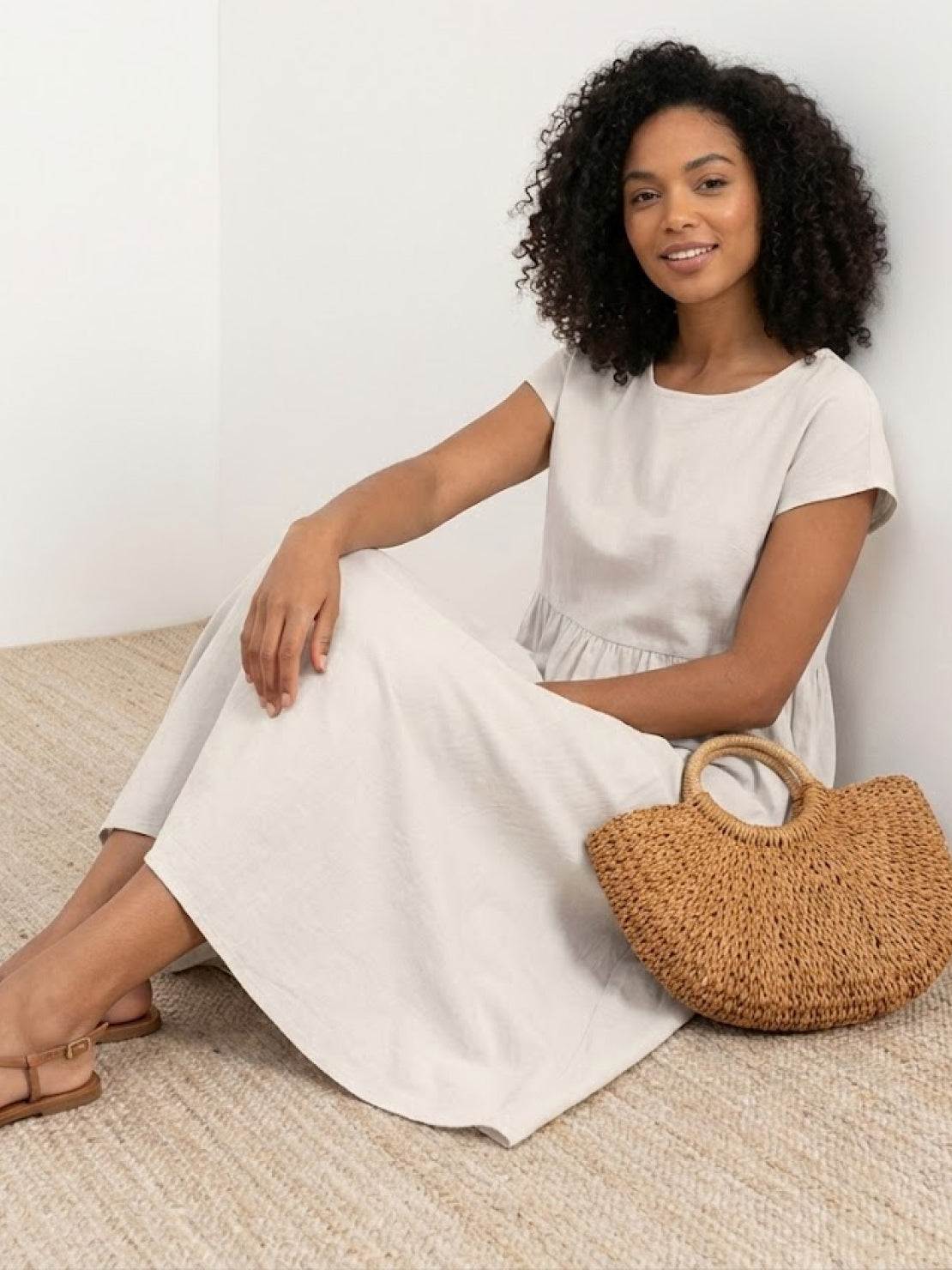 Woman wearing capped-sleeve voluminous pleated midi dress with flowing skirt and pockets