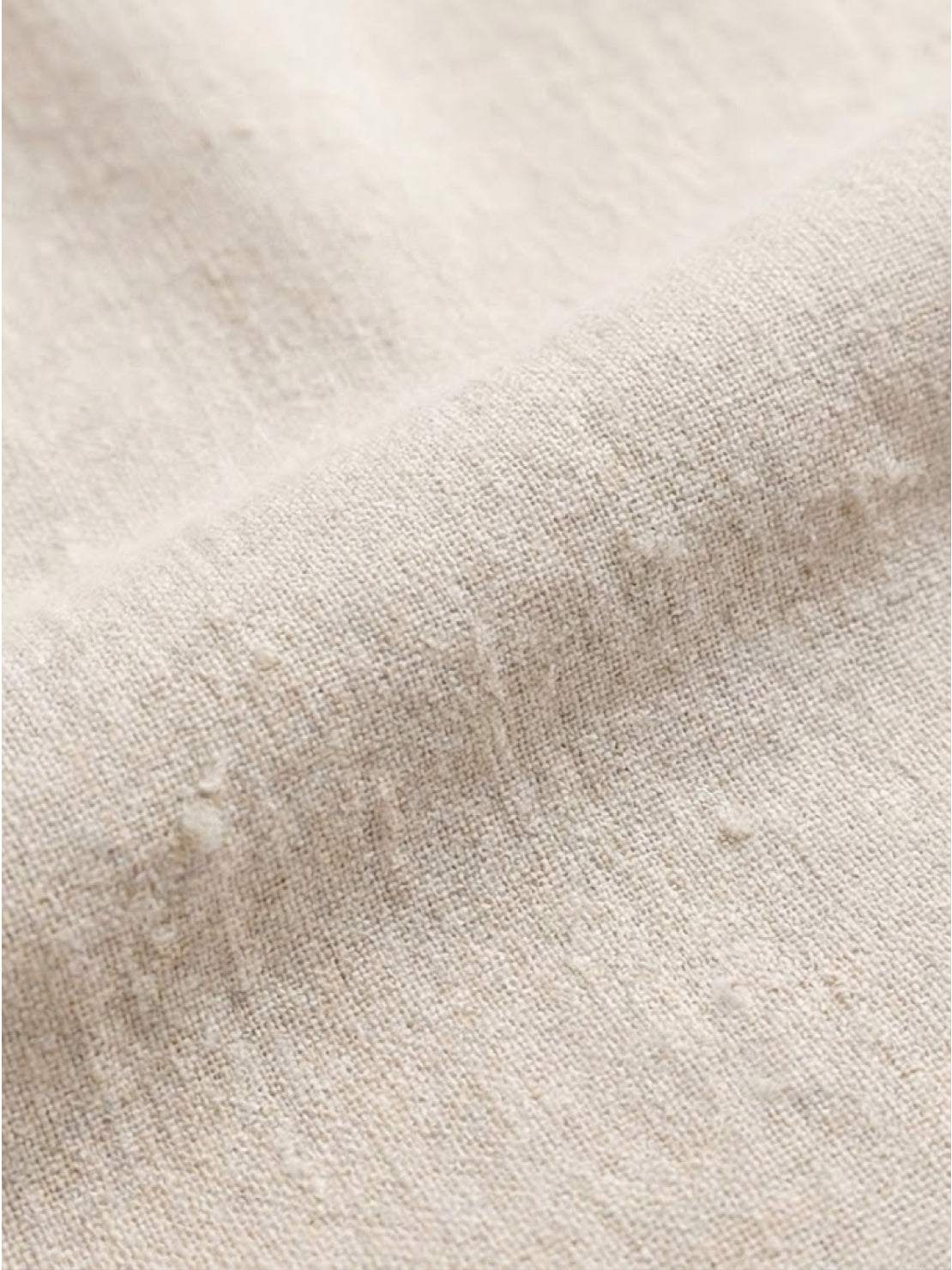 Woman wearing a capped-sleeve voluminous pleated midi dress with a flowy, stomach-flattening drape and pockets