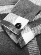 Close-up of Comfy Flannel Classic button-down shirt cuff with black button and grey plaid fabric