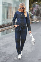 Woman wearing navy and black cotton-linen monochrome relaxed longline top and wide-leg pants set with white sneakers and sunglasses walking outdoors