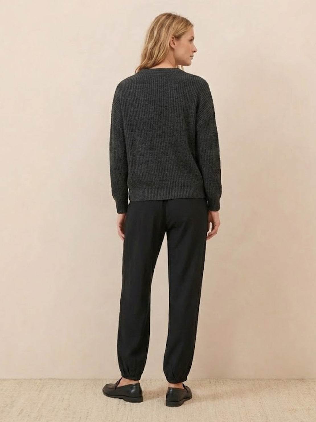 woman wearing European minimalism relaxed black sweater top and trouser set viewed from back