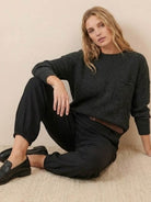 woman wearing European minimalism relaxed black sweater top and trouser set sitting on floor