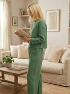 Woman wearing loose solid color two-piece set in green reading book in living room