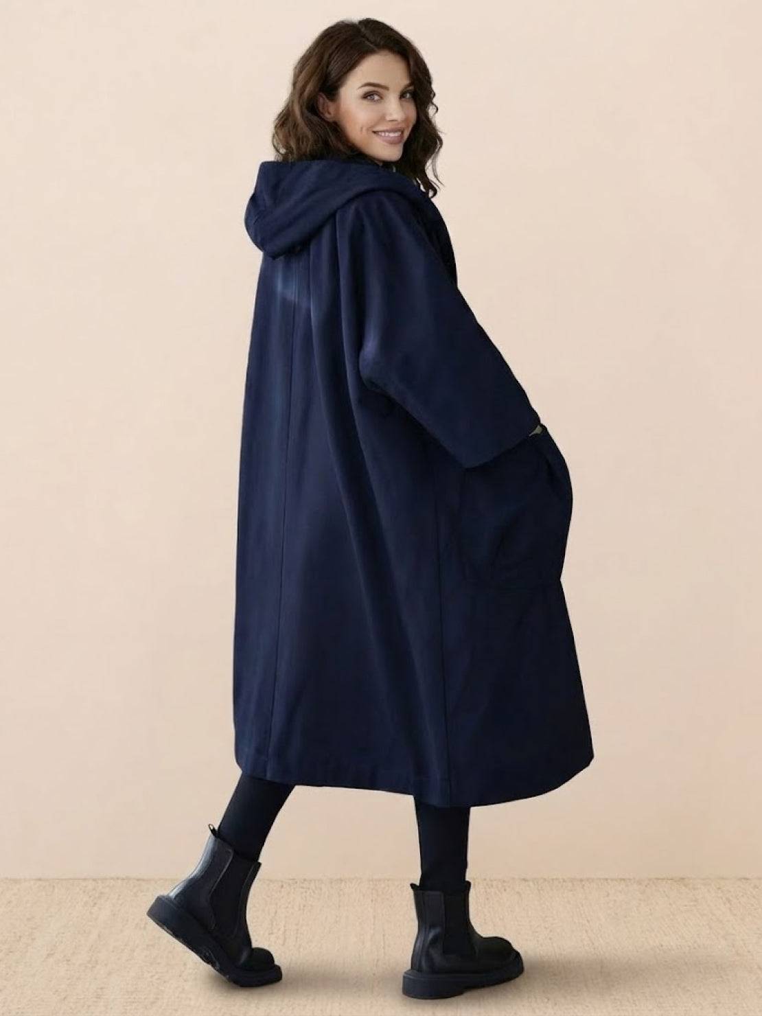 Woman wearing oversized navy waterproof windbreaker jacket with hood and pockets, longline design for layering and weather protection