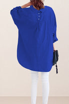 Back view of oversized linen shirt in blue with button and gathered details, paired with white pants.