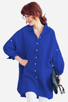 Woman wearing oversized linen shirt in vibrant blue with long sleeves and button-down front