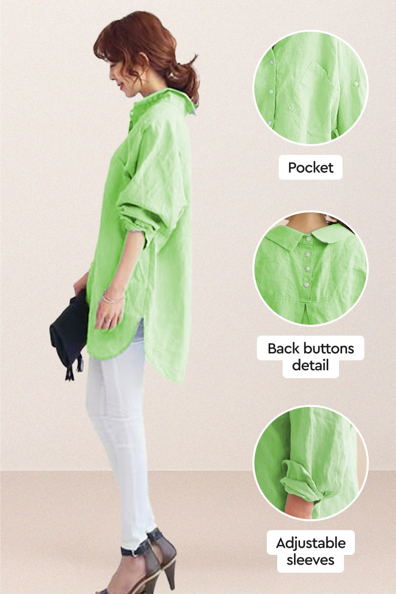 Side view of a woman wearing a green oversized linen shirt with back button details, adjustable sleeves, and a pocket, styled with white pants and heels