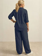 Back view of a woman wearing a navy oversized 100% cotton shirt and wide-leg pants co-ord set with rolled-up sleeves and relaxed fit