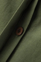 Close-up of oversized 100% cotton shirt fabric in olive green with brown button detail