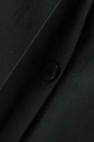 Close-up of oversized 100% cotton black shirt fabric with button detail