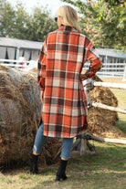 Woman wearing oversized medium-length plaid overshirt outdoors near hay bales
