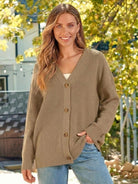 Relaxed fit oversized knit cardigan with button down front in neutral tone worn by smiling woman outdoors