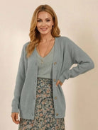 Woman wearing relaxed fit oversized button down knitwear cardigan in light grey with floral skirt