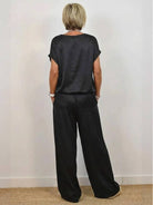 Woman wearing Silken Escape satin two-piece set with wide-leg pants and fitted top in soft flowing fabric