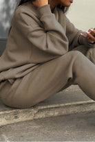 Woman wearing neutral toned cotton blend tracksuit sitting outdoors with relaxed posture