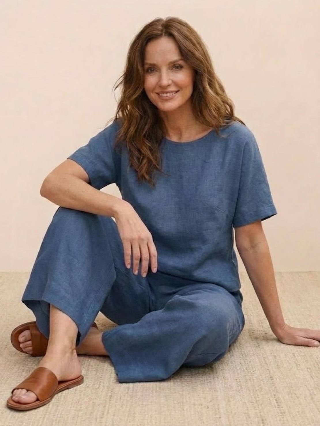 woman wearing blue loose fit co-ord set with wide-leg pants and short-sleeve top sitting on floor