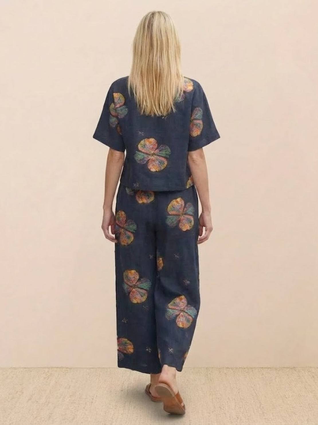 woman wearing loose fit co-ord set with floral print and wide-leg pants from back view