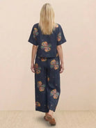woman wearing loose fit co-ord set with floral print and wide-leg pants from back view