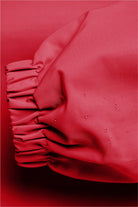 Close-up of red Rain Couture Windbreaker sleeve with water-resistant fabric and elastic cuff detailing.