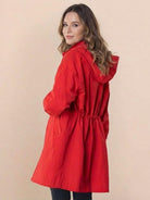 Woman wearing red oversized Rain Couture Windbreaker with hood and cinched waist, back view