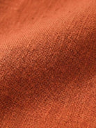 Close-up of soft lightweight cotton fabric texture in warm earthy orange for cotton dress