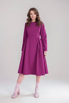 Woman wearing a purple water-repellent rain A-line dress coat with long sleeves and fitted waist belt